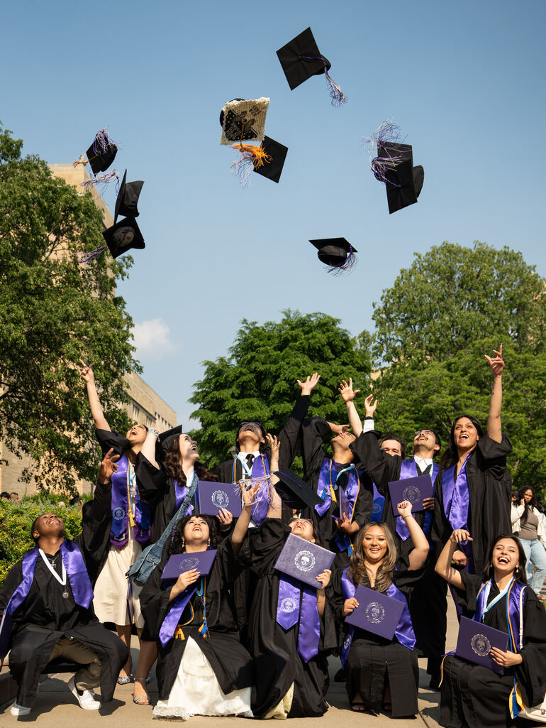 DFC students throw their grad caps in the air outside after graduation