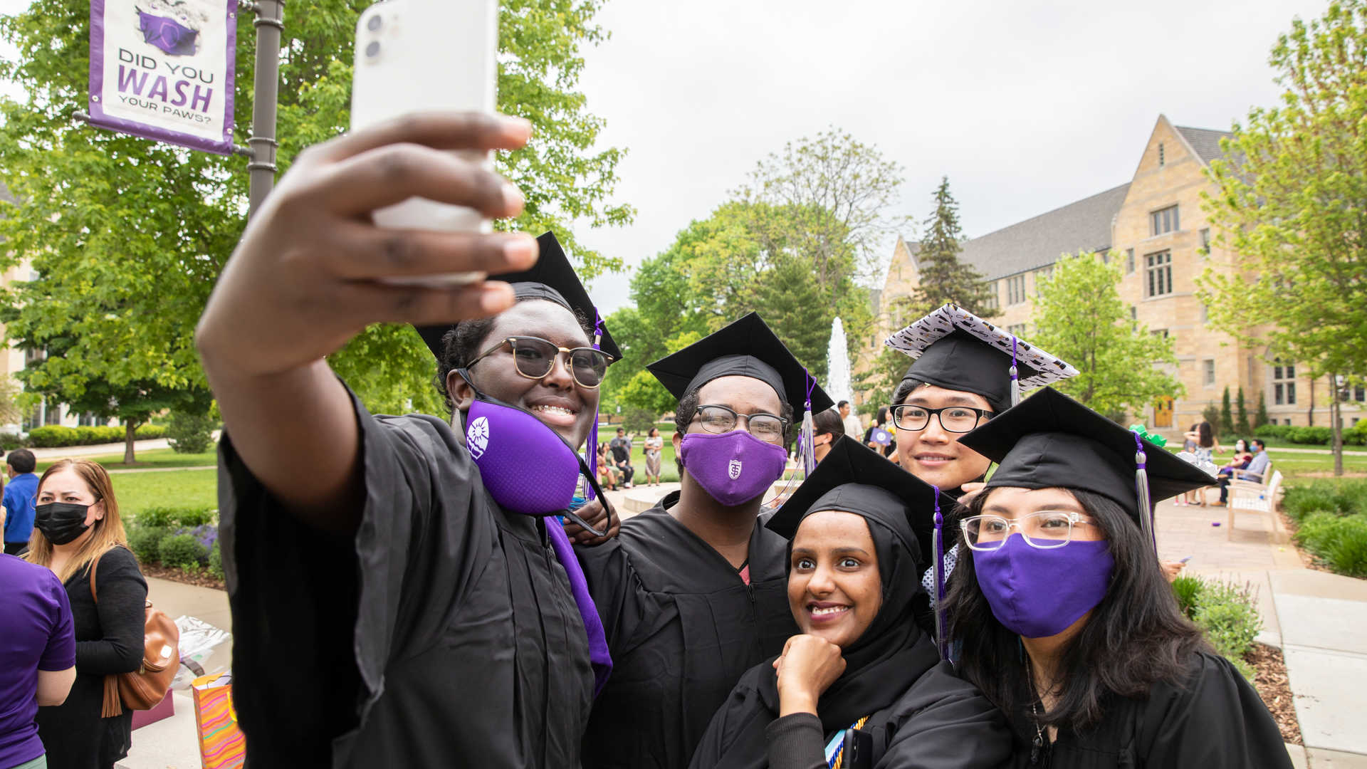Group of students in caps and gowns taking a selfie at graduation.